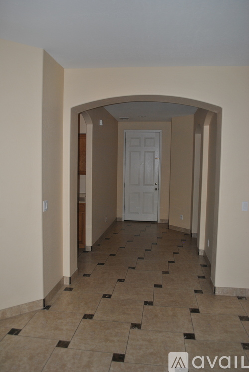 A hallway with a tiled floor and a white door.