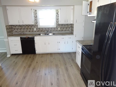 A kitchen with black appliances and white cabinets.