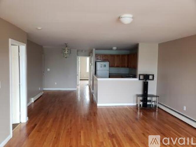 A spacious living room with hardwood floors and a kitchen in the background.
