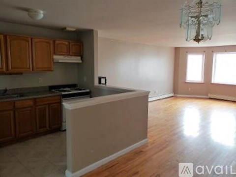 A kitchen with wooden cabinets and a countertop with a chandelier hanging from the ceiling.