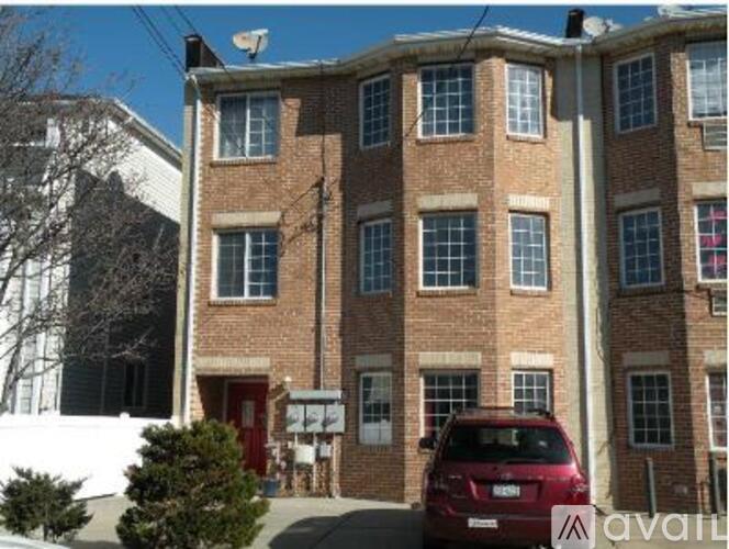 A red car is parked in front of a brick building.