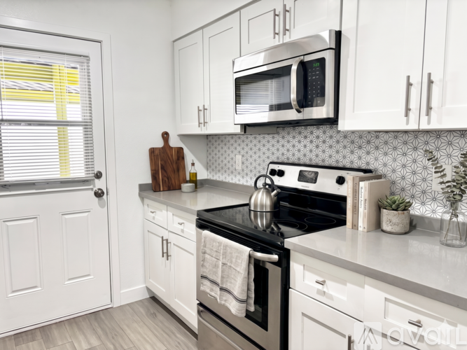 A modern kitchen with white cabinets and a black stove top.