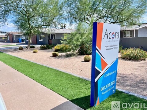 A sign for Acora Professional Property Management stands in front of a building.