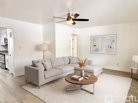 A living room with a grey sofa, a coffee table, and a ceiling fan.