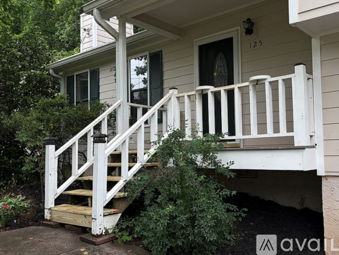 A white wooden staircase with a black door and a window is in front of a house.