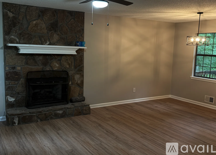 A room with a stone fireplace and wooden flooring.