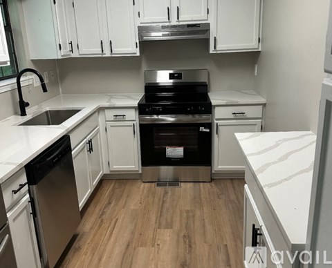 A kitchen with a black dishwasher and stove top oven.
