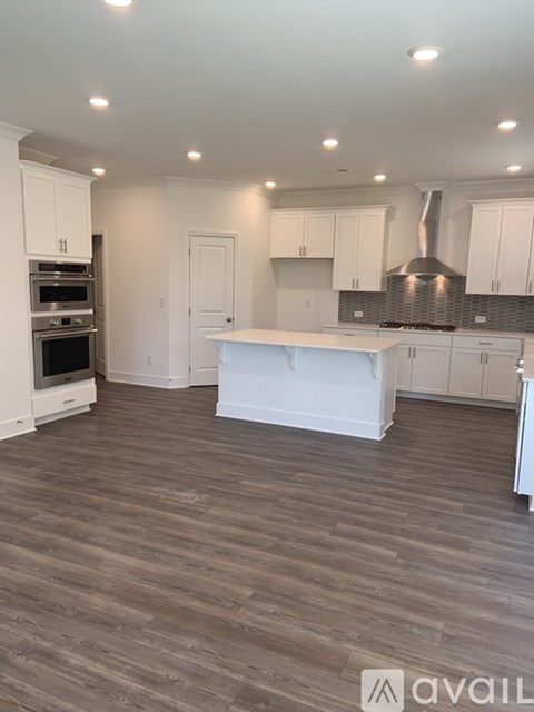 A kitchen with white cabinets and a wooden floor.