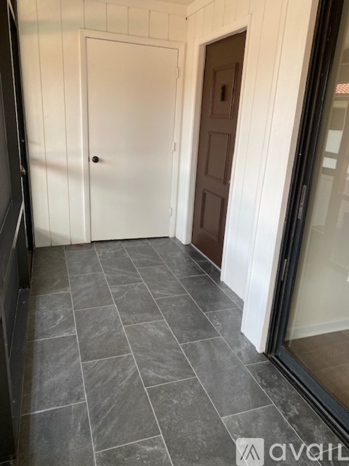A hallway with a slate tile floor and white walls.