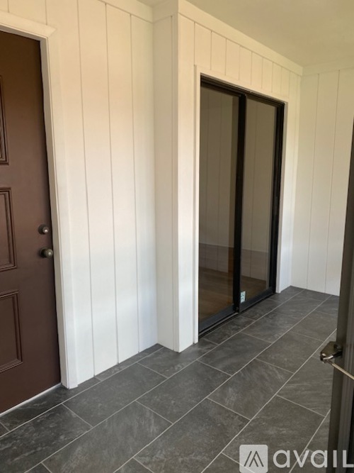 A hallway with a brown door and a glass door.