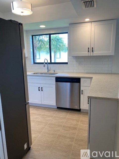 A kitchen with a black refrigerator, white cabinets, and a stainless steel dishwasher.