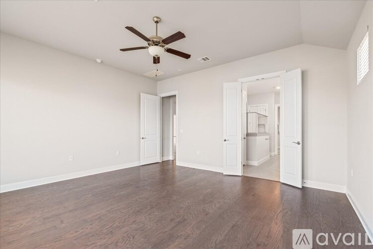 A spacious room with a ceiling fan and wooden flooring.