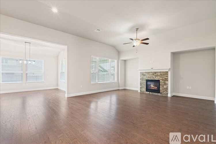 A spacious living room with wood flooring and a fireplace.