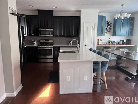 A kitchen with a white island and black cabinets.