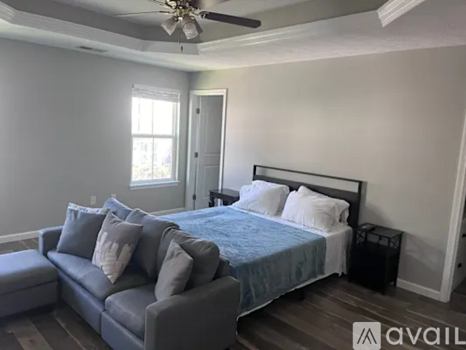 A bedroom with a bed, a couch, and a ceiling fan.