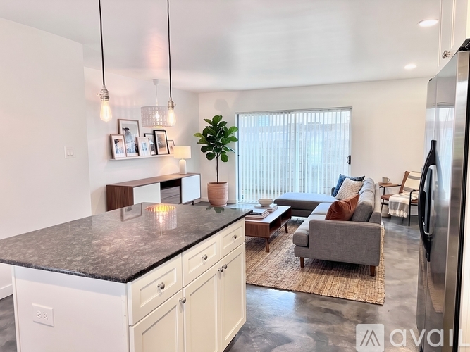 A kitchen with a granite countertop and a refrigerator on the right side.