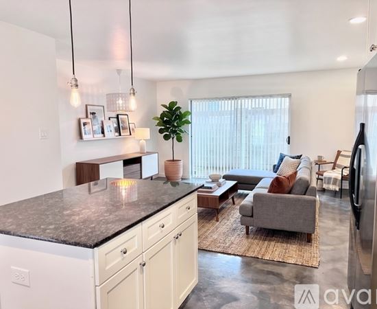 A kitchen with a granite countertop and a refrigerator on the right side.