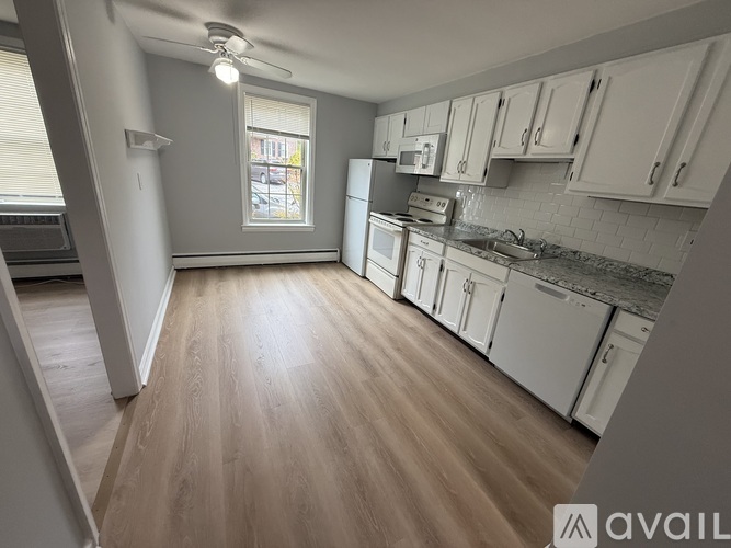 A kitchen with white cabinets and a wooden floor.