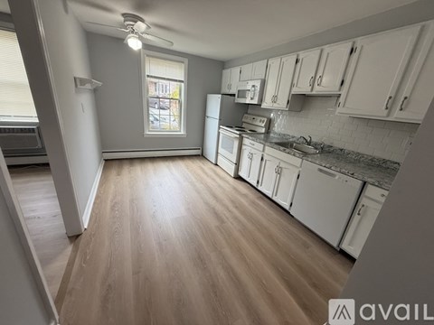 A kitchen with white cabinets and a wooden floor.
