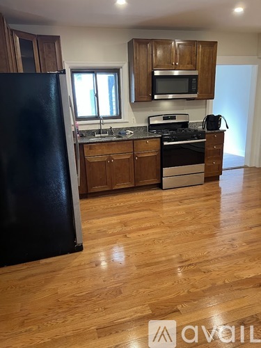 A kitchen with wooden cabinets and a black refrigerator.
