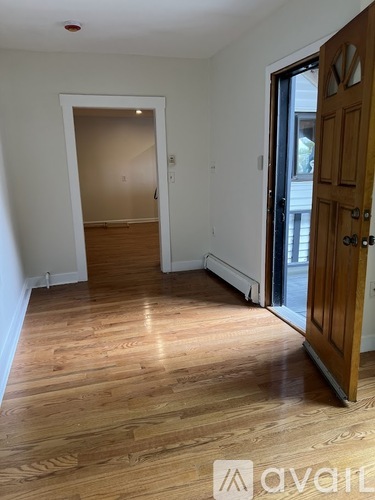 A room with wooden floors and a door on the right.