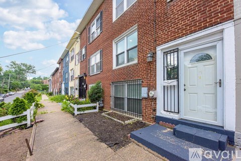 A brick house with a white door and a small garden in front.