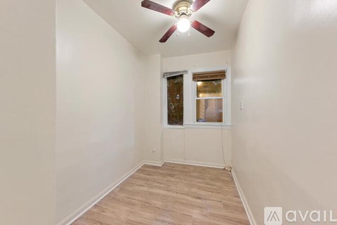 A room with a ceiling fan and a window with a view of a building outside.
