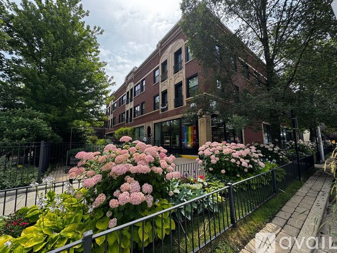 A building with a fence and flowers in front.