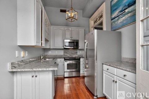 A kitchen with white cabinets and a marble countertop.