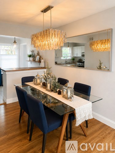 A modern dining room with a glass table and dark blue chairs.