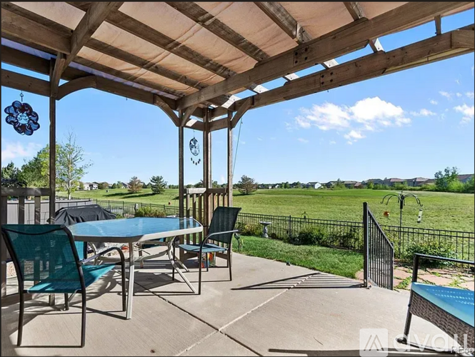 A patio with a table and chairs overlooking a green field.