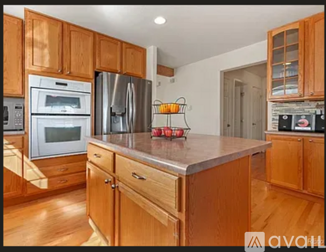 A kitchen with wooden cabinets and a stainless steel refrigerator.