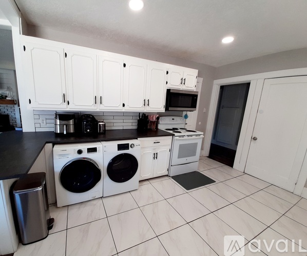 A kitchen with white cabinets and black countertops.