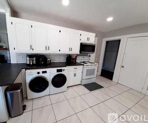 A kitchen with white cabinets and black countertops.