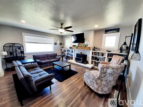 A living room with a grey couch, a black chair, and a television on the wall.