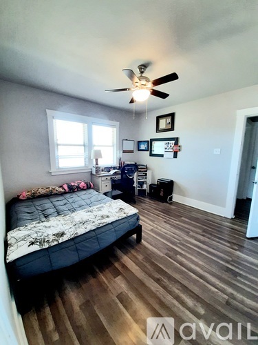 A bedroom with a bed, a ceiling fan, and a window.