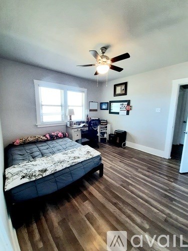 A bedroom with a bed, a ceiling fan, and a window.