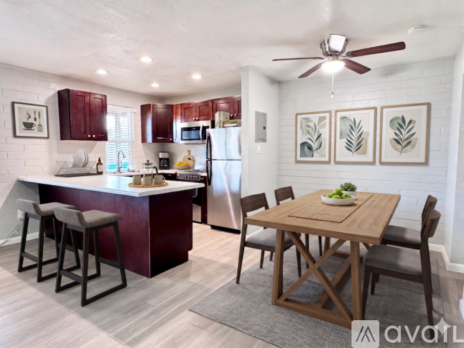 A kitchen with a wooden table and chairs, a refrigerator, and a ceiling fan.