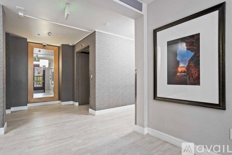 A hallway with a framed picture on the wall and a door on the left.