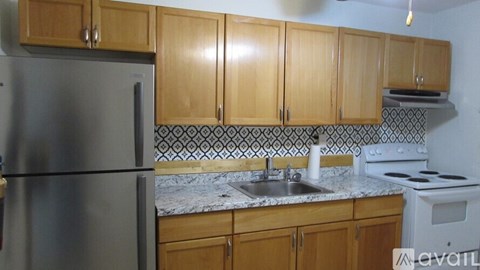 A kitchen with wooden cabinets and a stainless steel refrigerator.