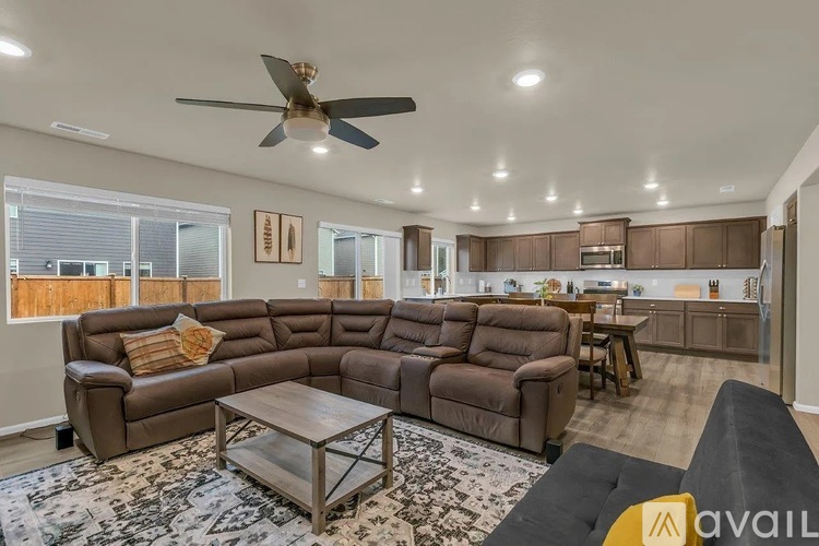 A living room with a brown couch and a ceiling fan.