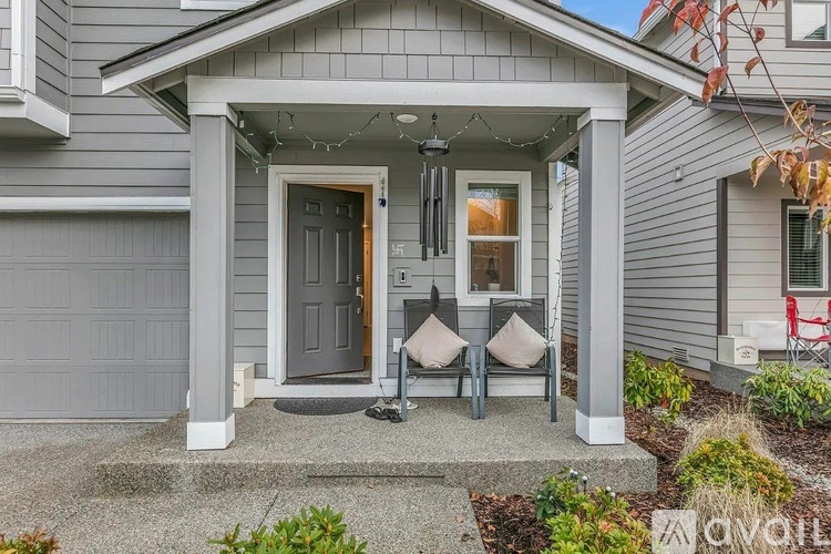 A house with a grey siding and a white door is for sale.