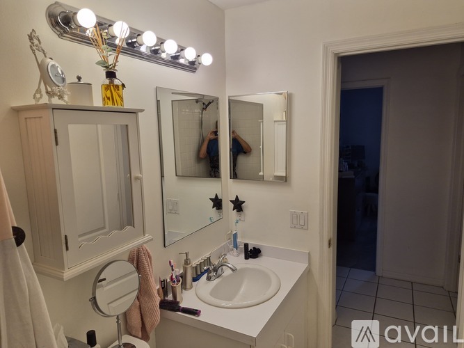 A bathroom with a sink, mirror, and lights.