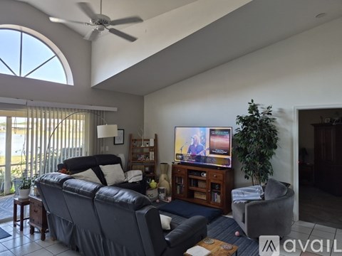 A living room with a grey sofa and a television on a wooden stand.