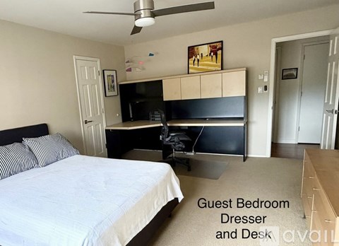 A guest bedroom with a dresser and desk.