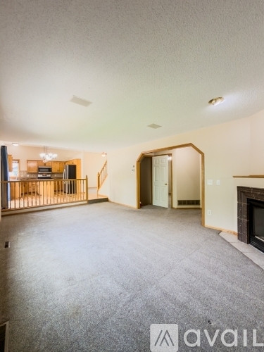 A spacious living room with a fireplace and a dining area in the background.