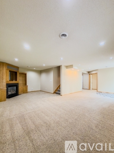 A spacious room with a fireplace and carpeted floor.
