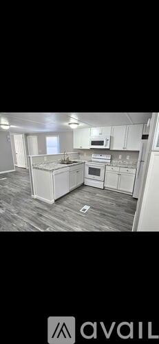 A kitchen with white cabinets and a wooden floor.