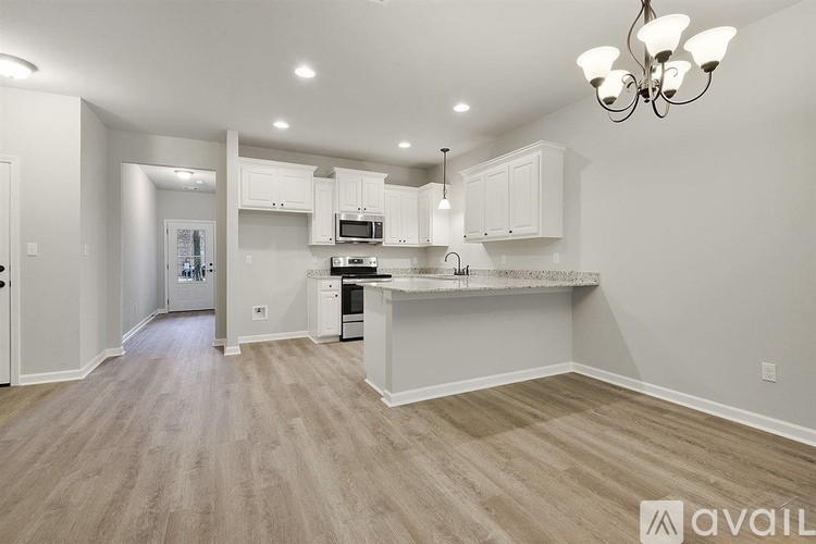 A kitchen with white cabinets and a wooden floor.