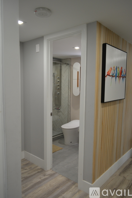 A bathroom with a toilet, a shower, and a painting on the wall.